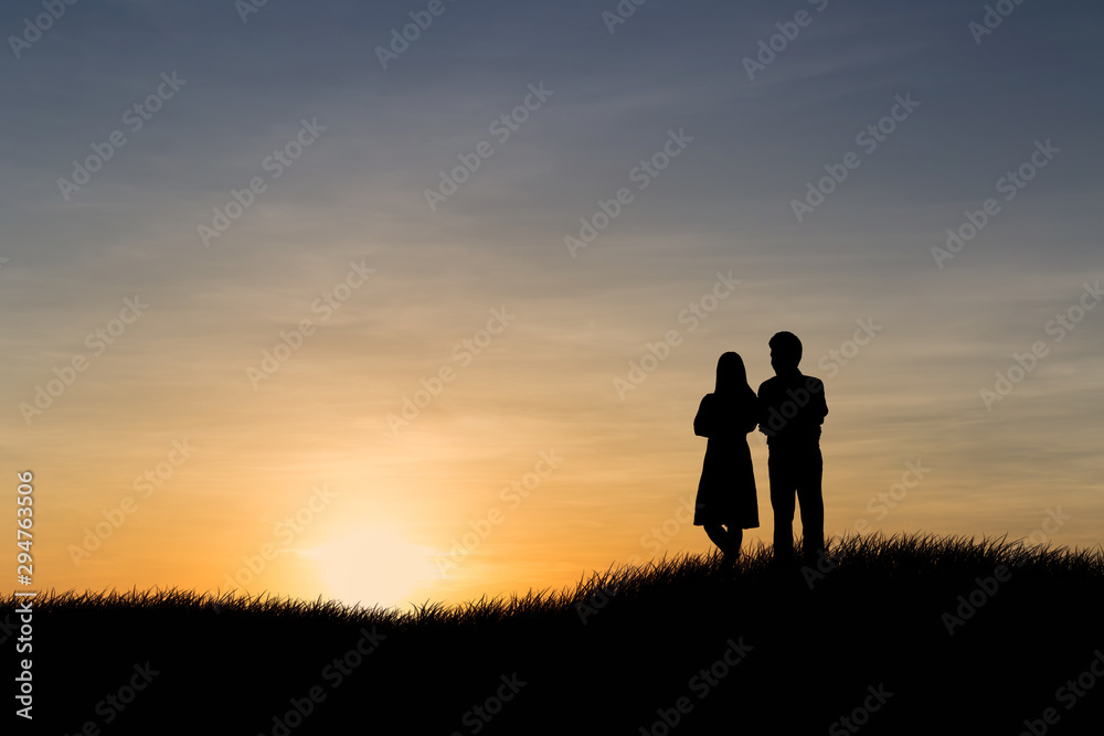 Silhouettes of couple man and woman in nature sunset background. Love concept.