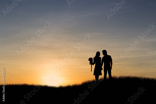 Silhouettes of couple man and woman in nature sunset background. Love concept.