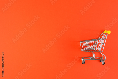 Shopaholic. Buyer. Shopping concept. Close-up. Isolated shopping trolley on a red background. Copy space.