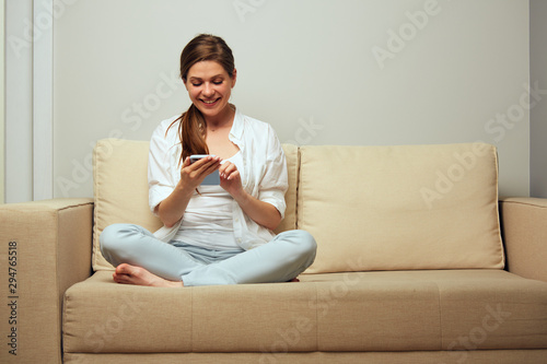 woman sitting on sofa using cell smart phone with mobile internet.