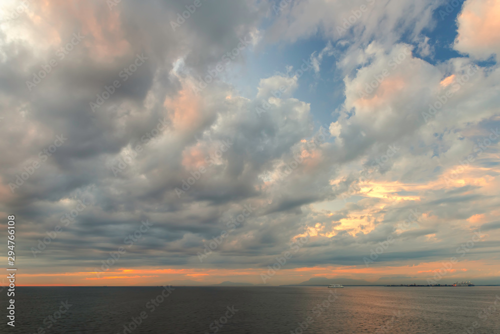 cumulus clouds in the rays of the setting sun over the ocean near the mountains cumulus clouds in the rays of the setting sun over the ocean near the mountains