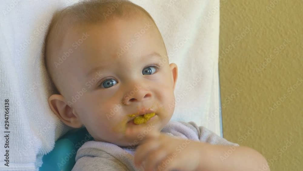 Baby boy being fed puree by mother's hand and making a mess, 10 month old Baby boy being fed puree by mother's hand and making a mess, 10 month old