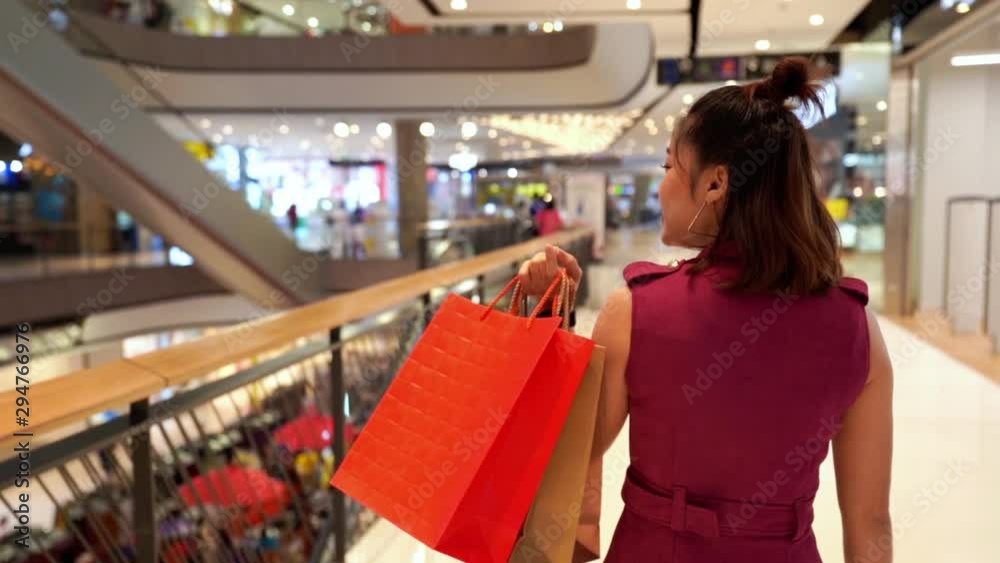 slow-motion of young woman walking with shopping bags in the mall
