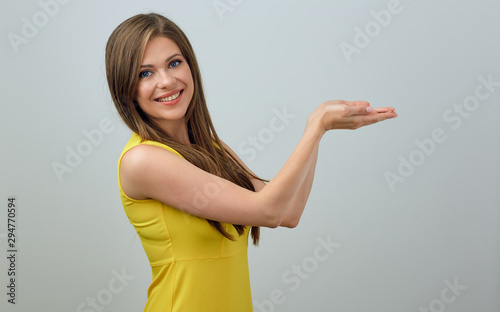 Smiling woman in yellow dress holding empty hand.