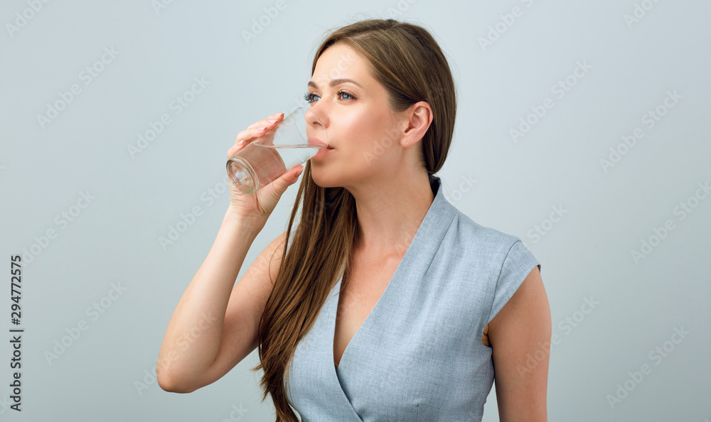Young woman in business dress drinking water from glass. Young woman in business dress drinking water from glass.
