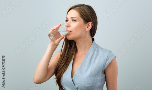 Young woman in business dress drinking water from glass.