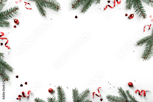 Creative frame made of Christmas fir branches on white background with red decoration, pine cones. Xmas and New Year greeting card, winter holiday. Flat lay, top view