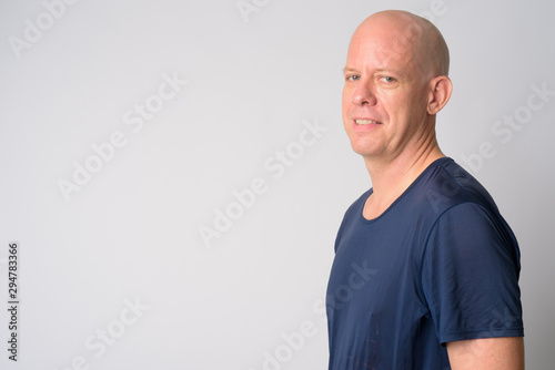 Closeup profile view of happy mature handsome bald man looking at camera
