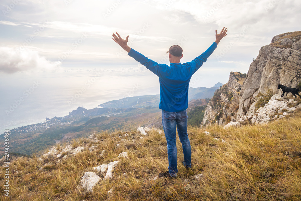 Traveler stands on a high mountain with his hands up. Crimea Traveler stands on a high mountain with his hands up. Crimea