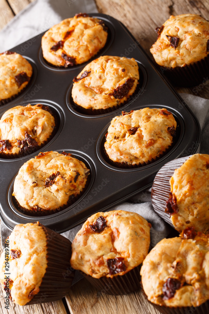 muffins with sun-dried tomatoes and cheddar cheese close-up in a baking dish on the table. vertical muffins with sun-dried tomatoes and cheddar cheese close-up in a baking dish on the table. vertical