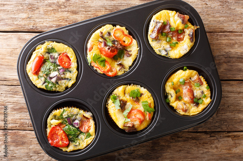 egg muffins omelet with bacon, tomatoes, spinach and mushrooms close-up in a baking dish. Horizontal top view