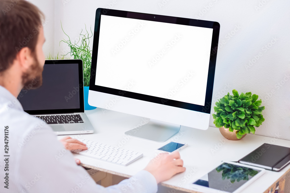 Young man working with computer with blank screen. Mock up design. Young man working with computer with blank screen. Mock up design.