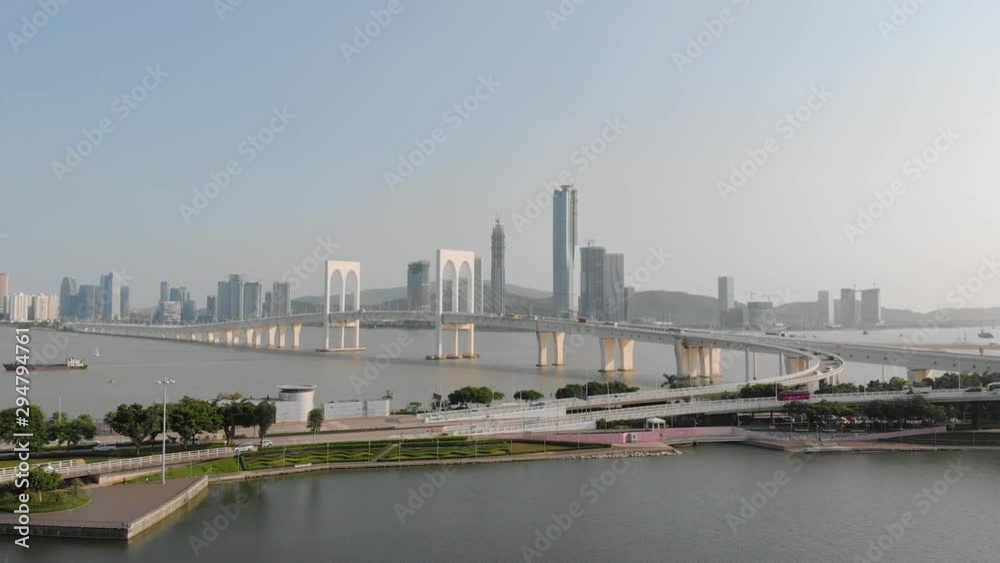 Drone approach shot of traffic crossing Sai Van Bridge in Macau with mainland China skyscrapers in background Drone approach shot of traffic crossing Sai Van Bridge in Macau with mainland China skyscrapers in background