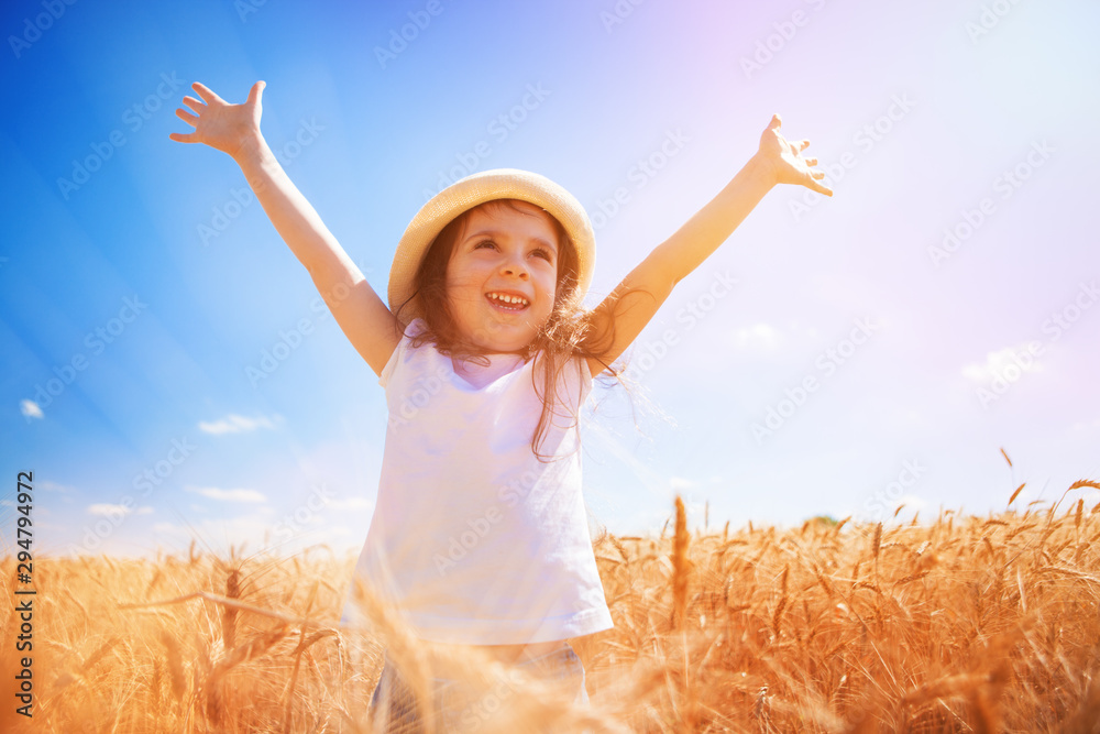 Happy girl walking in golden wheat, enjoying the life in the field. Nature beauty, blue sky and field of wheat. Family outdoor lifestyle. Freedom concept. Cute little girl in summer field Happy girl walking in golden wheat, enjoying the life in the field. Nature beauty, blue sky and field of wheat. Family outdoor lifestyle. Freedom concept. Cute little girl in summer field