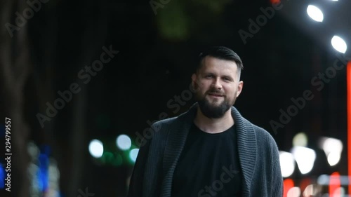 Close-up of a handsome bearded man happily sending a kiss and then leaving in the evening street