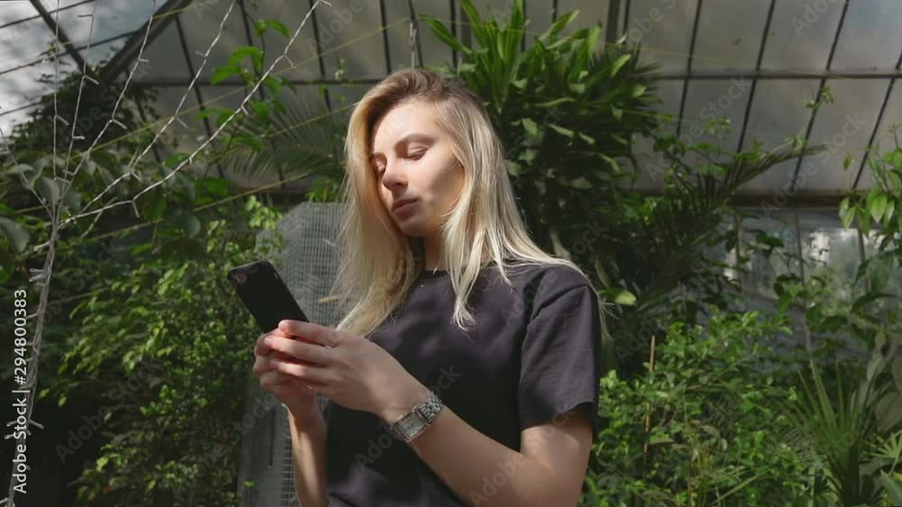 Pretty blonde girl blogger using a smartphone in botanical garden, young caucasian woman use mobile in social internet media technology 5g Pretty blonde girl blogger using a smartphone in botanical garden, young caucasian woman use mobile in social internet media technology 5g