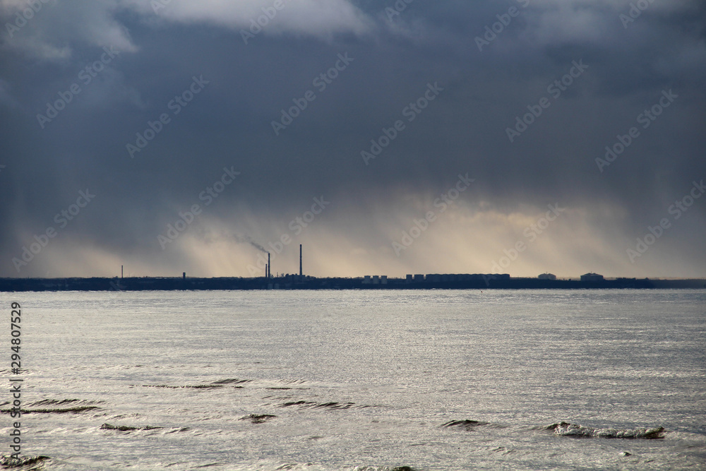 Industrial plant on seashore and smoke in dark sky
