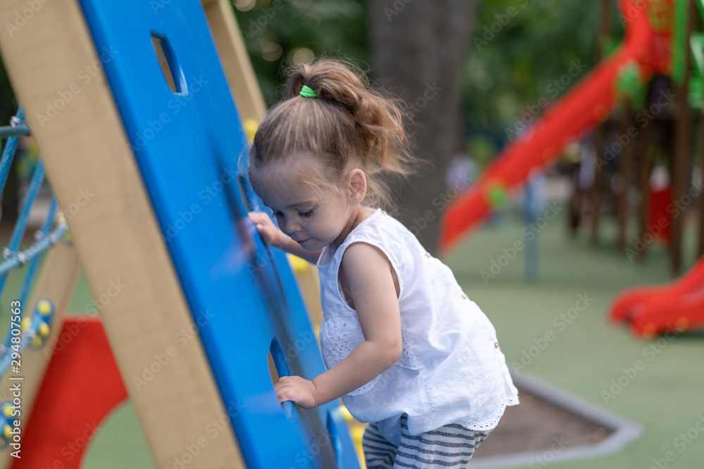 Little Caucasian girl plays on playground climbs stairs upstairs. Little Caucasian girl plays on playground climbs stairs upstairs.