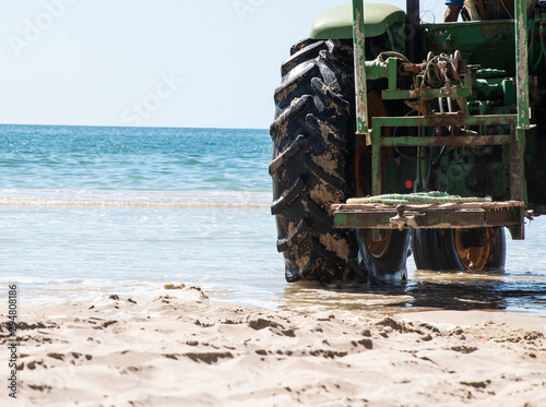 Rueda y parte de un tractor en la orilla de la playa  photo