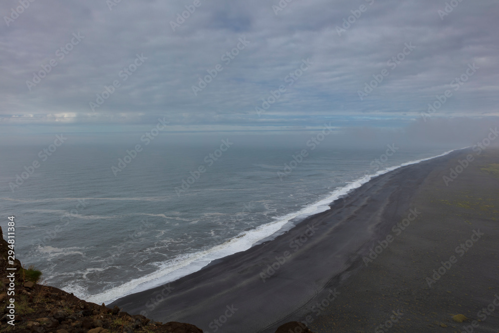 Reynisfjara Black Sand Beach, found on the south coast of Iceland near the village of village of Vik i Myrdal, seen from a cliff during a cloudy morning.