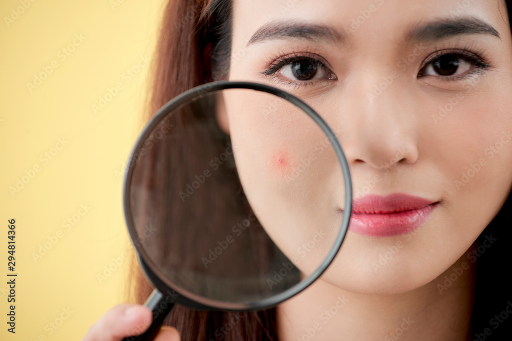 Woman with magnifying glass isolated on a yellow background Woman with magnifying glass isolated on a yellow background