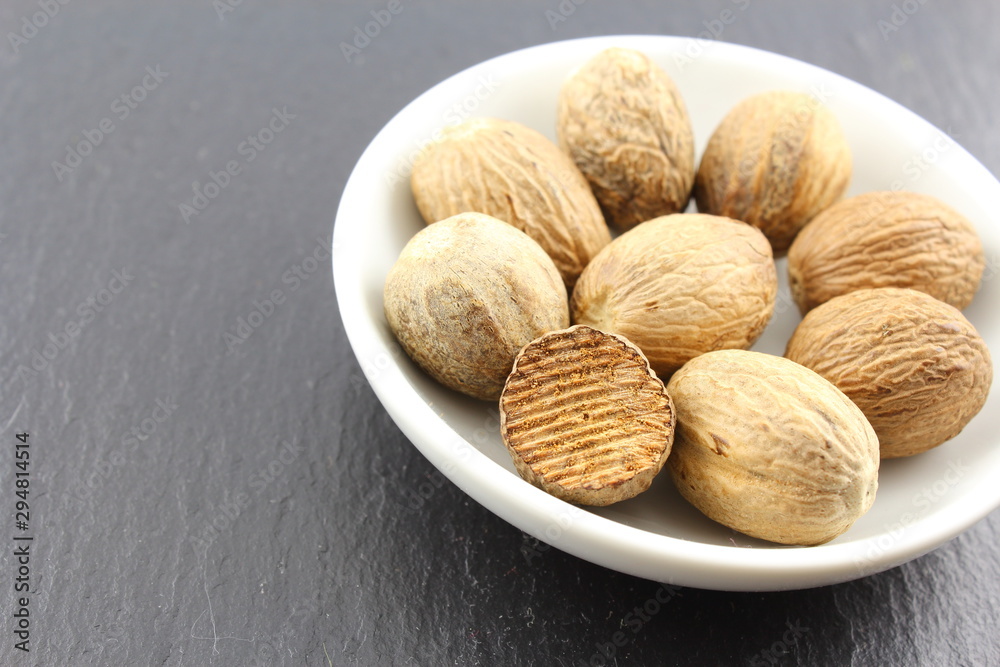 nutmeg seeds in a small white bowl nutmeg seeds in a small white bowl