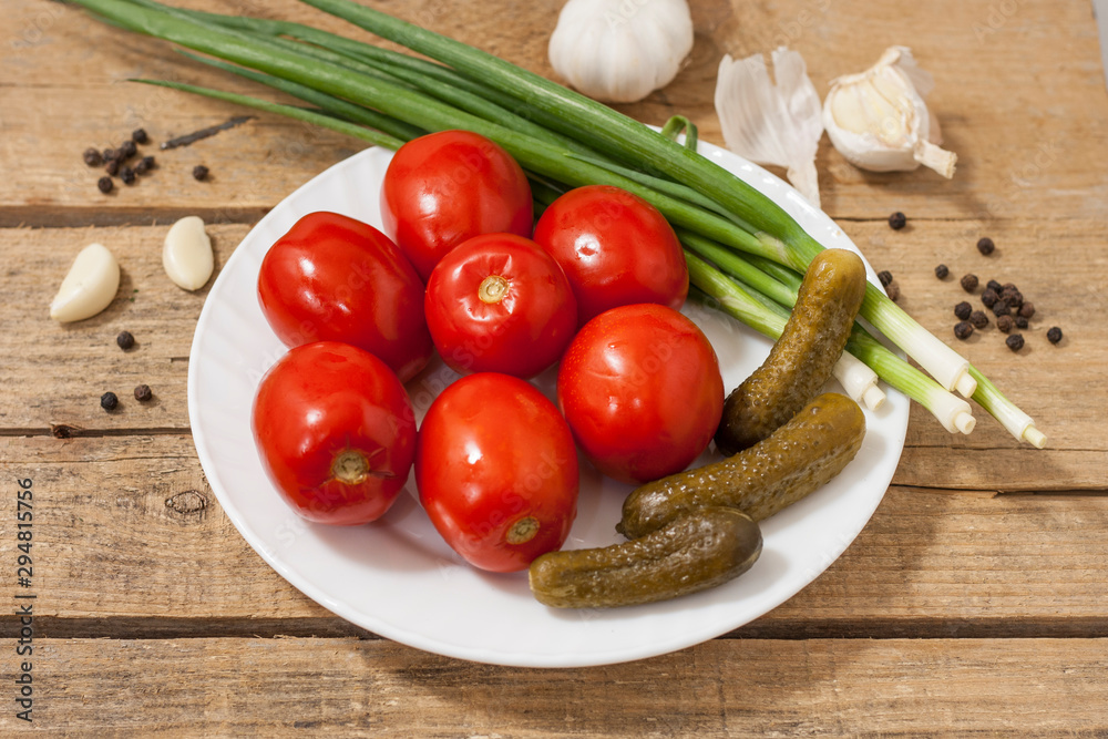 Fermented food on a white plate on an old wooden table. Pickled tomatoes and cucumbers. Salt for the winter. Traditional snack for alcohol. Fermented food on a white plate on an old wooden table. Pickled tomatoes and cucumbers. Salt for the winter. Traditional snack for alcohol.