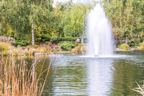 Fragment of the park in Mezhyhiria near Kiev, fountains on the lake. Scenery of nature with sunlight.	 photo