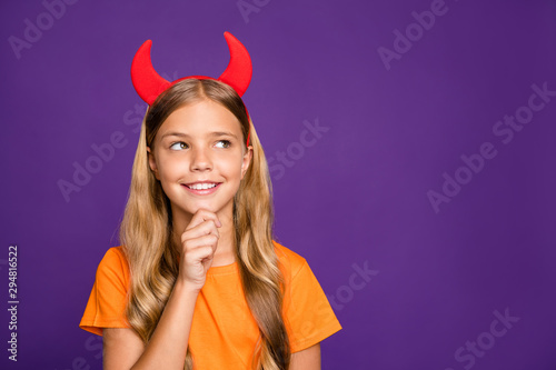 Photo of pretty little lady headband horns on head looking empty space thinking over evil trick on helloween party wear orange t- shirt isolated purple color background