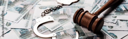 Foto panoramic shot of wooden gavel near handcuffs on russian money