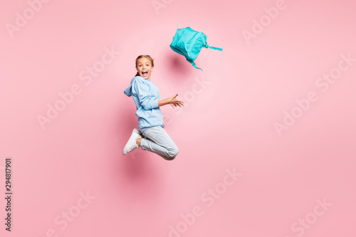 Full length photo of pretty little lady jumping high go home after studying week throwing pupil backpack up air wear casual clothes isolated pink color background