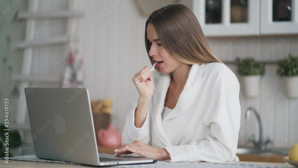 Girl brushes her teeth with toothbrush and uses laptop to check email in morning Girl brushes her teeth with toothbrush and uses laptop to check email in morning