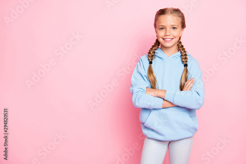 Photo of cheerful positive kind friendly cute girl standing confidently with arms crossed near empty space to be fulfilled with ads isolated over pastel color background