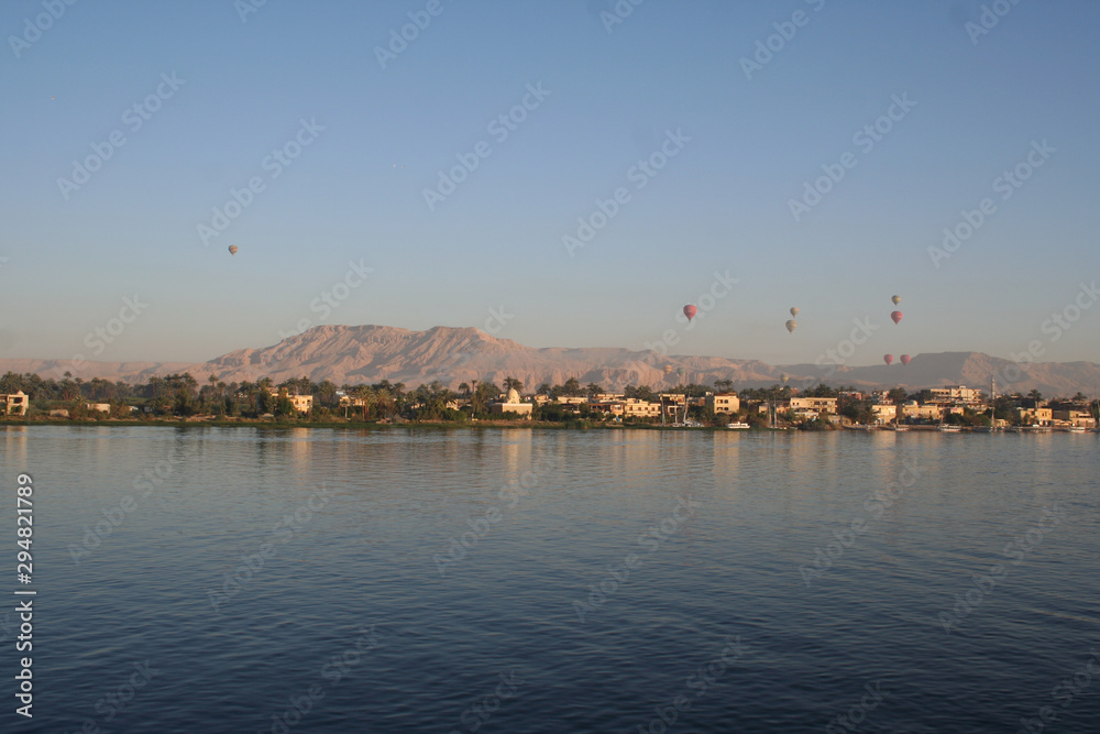 Hot air balloons floating over the Nile River in Luxor at sunrise