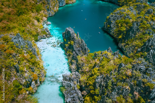 Aerial drone view of a beautiful tropical Big Lagoon at Miniloc Island, El Nido, Philippines. Tourist kayaking surrounded by jagged limestone cliffs. Bacuit, Palawan