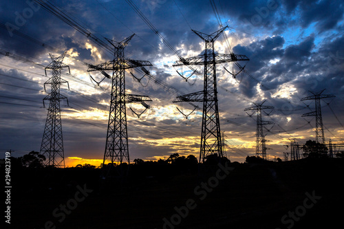 High tension electricity pylons silhouetted against an evening sky.