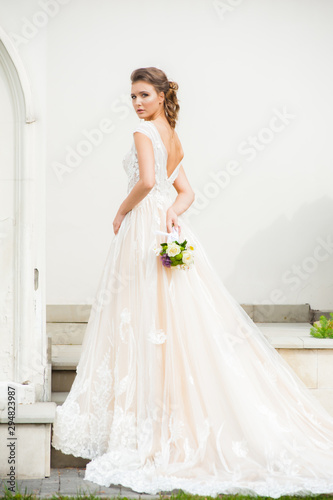 Beautiful happy bride in long wedding dress with wedding bouquet