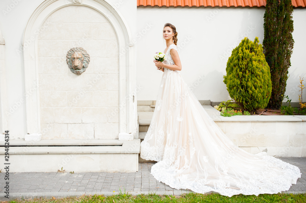 Fototapeta premium Beautiful happy bride in long wedding dress with wedding bouquet