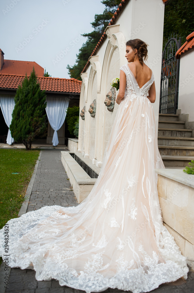 Fototapeta premium Bride in long wedding dress with bouquet outdoor