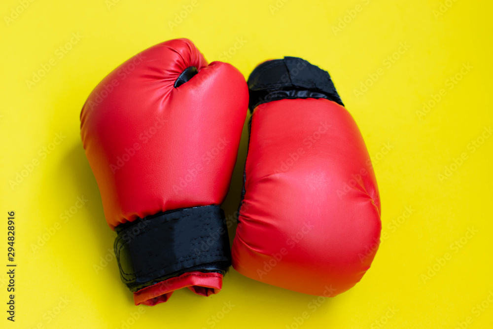 Red boxing gloves on a yellow background.