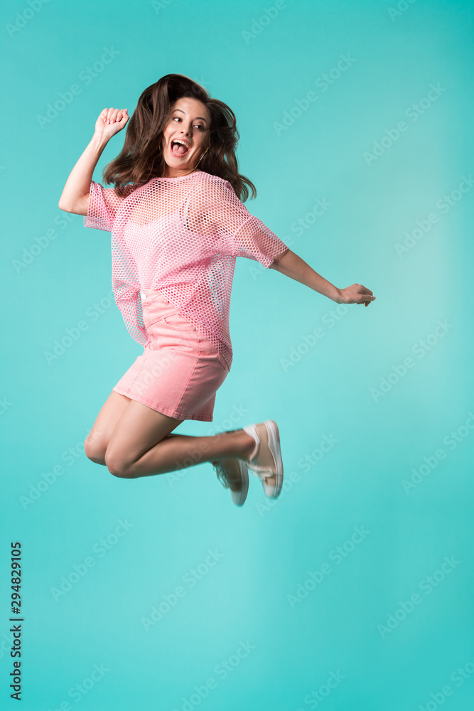 excited girl with open mouth in pink outfit jumping isolated on turquoise excited girl with open mouth in pink outfit jumping isolated on turquoise