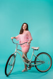 excited girl in pink outfit with retro bike on turquoise background