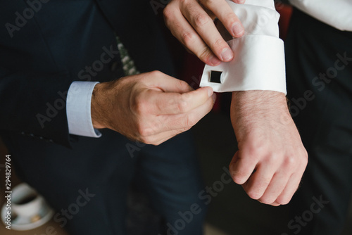 Wedding fashion for men. Closeup of caucasian man putting the cufflinks on the groom s shirt.