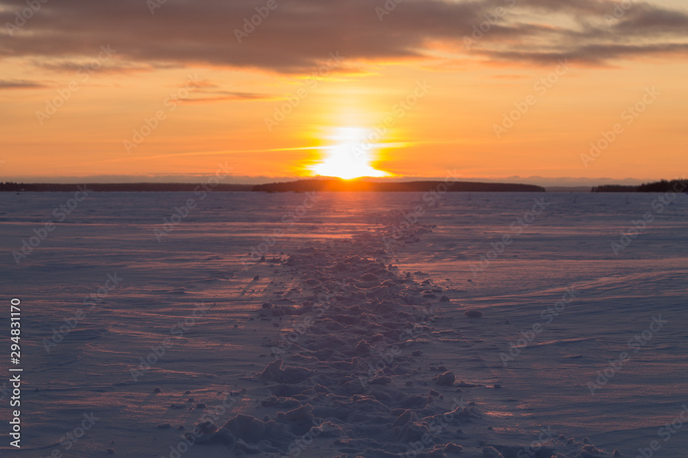 Lots of footprints in the snow. Footprints going into the sunset. Orange sunrise