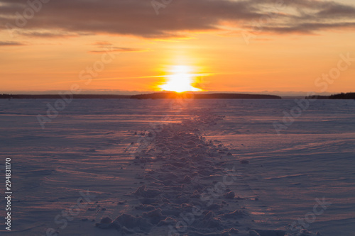 Lots of footprints in the snow. Footprints going into the sunset. Orange sunrise