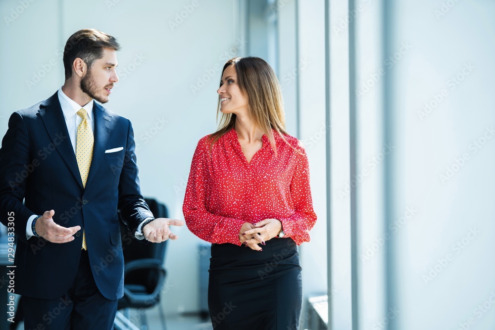 Businessman and businesswoman talking while walking in modern office Businessman and businesswoman talking while walking in modern office