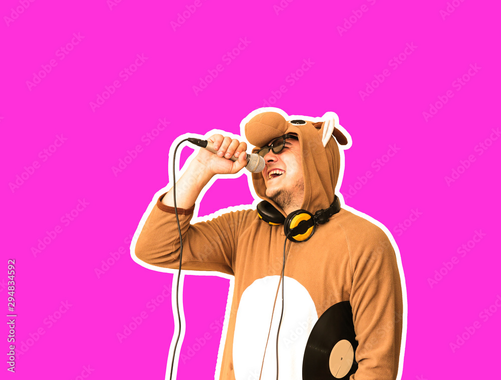 Obraz premium Man in cosplay costume of a cow singing karaoke isolated on purple background. Guy in the funny animal pyjamas sleepwear holding microphone. Funny photo. Party ideas. Disco music.