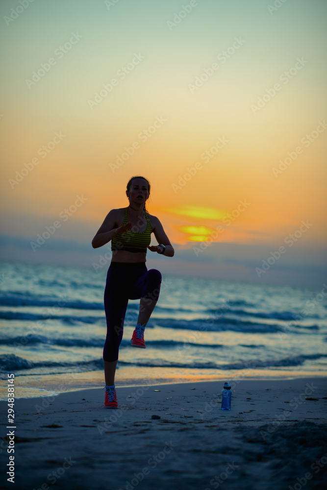 fit sports woman on seashore in evening training