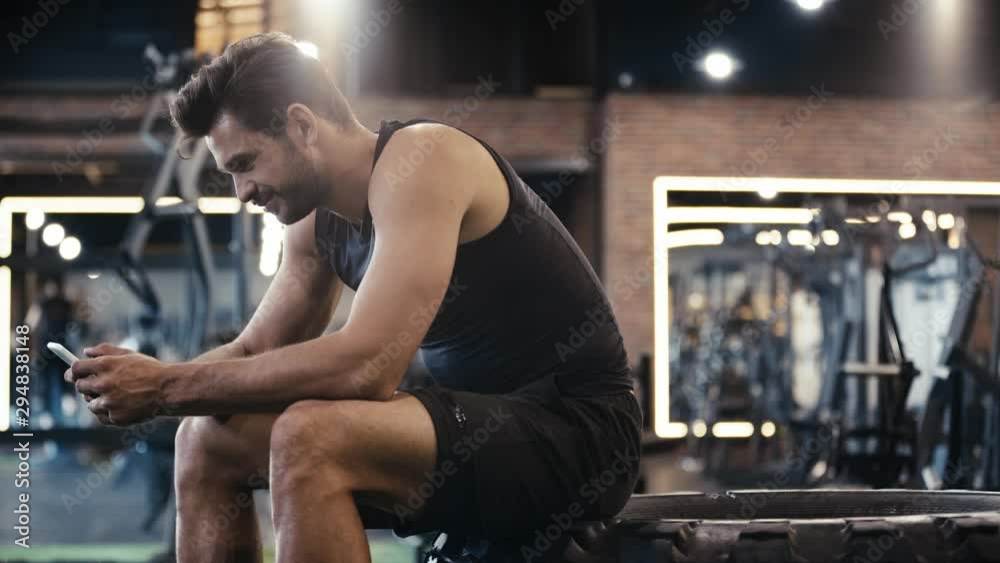 happy sportsman using smartphone in gym happy sportsman using smartphone in gym
