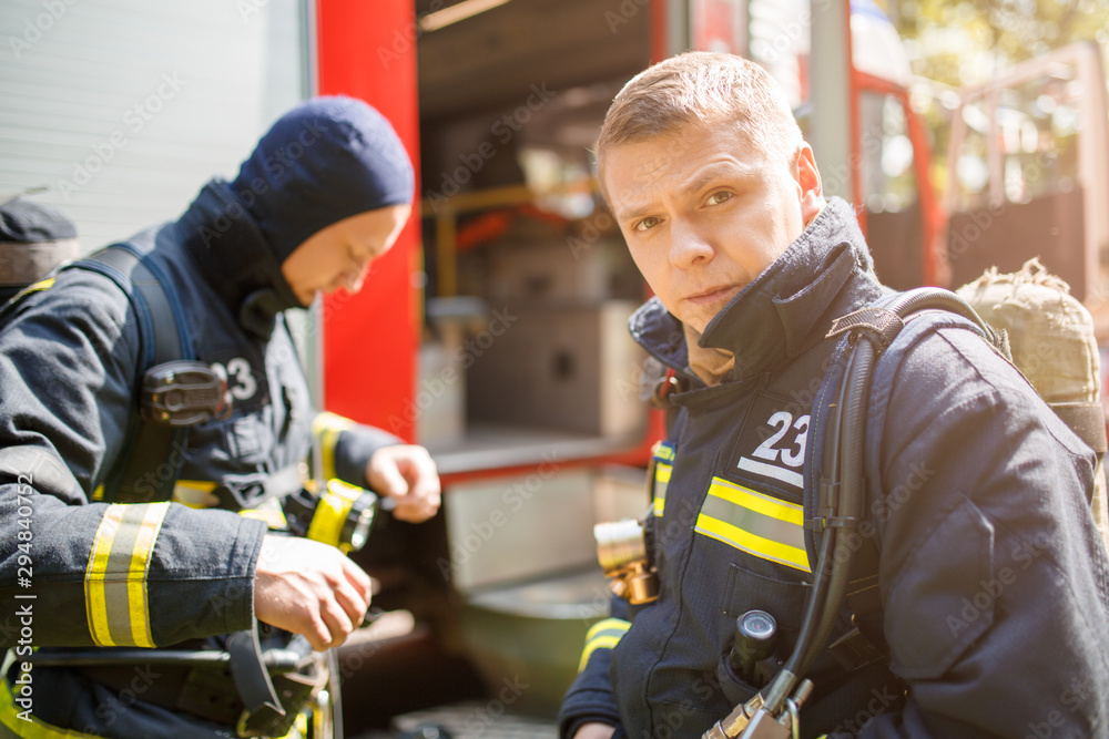 Two firefighters standing near fire engine. Two firefighters standing near fire engine.